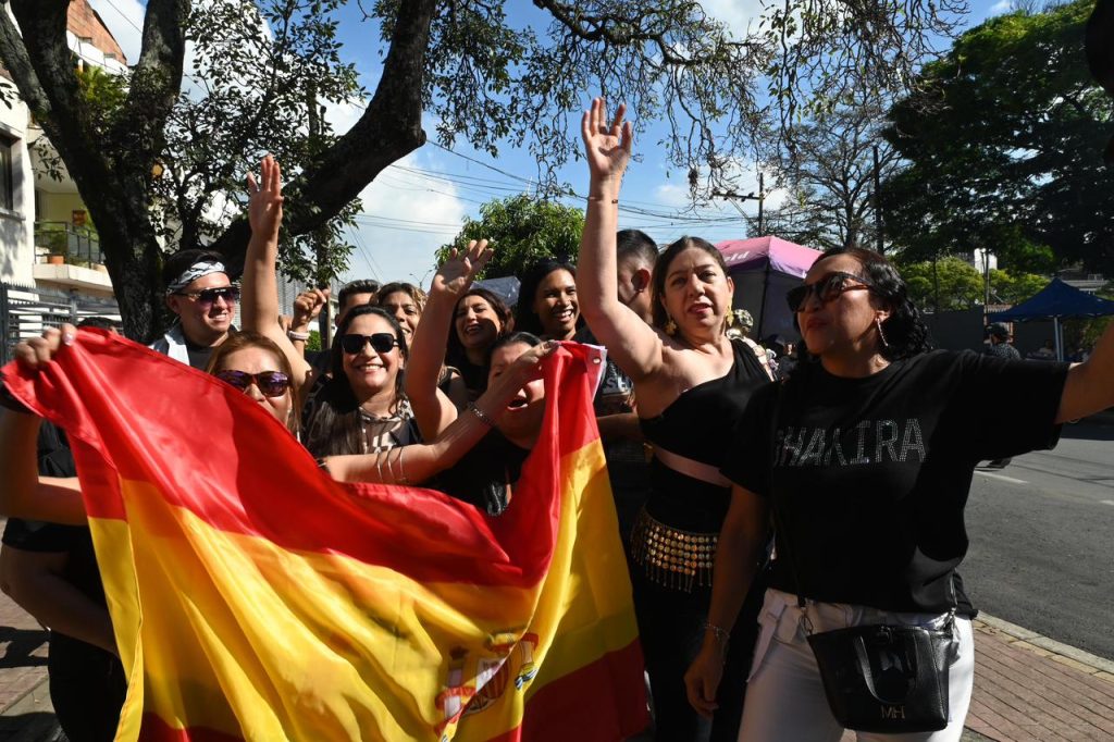 Shakira cantando en el estadio Pascual Guerrero de Cali, Colombia, mientras el público ilumina con luces de teléfono, simbolizando el impacto económico y el éxito turístico del evento.