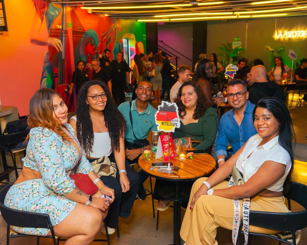 Multitud de personas interactuando y practicando idiomas en un evento nocturno con música en el rooftop La Azotea de Cali.